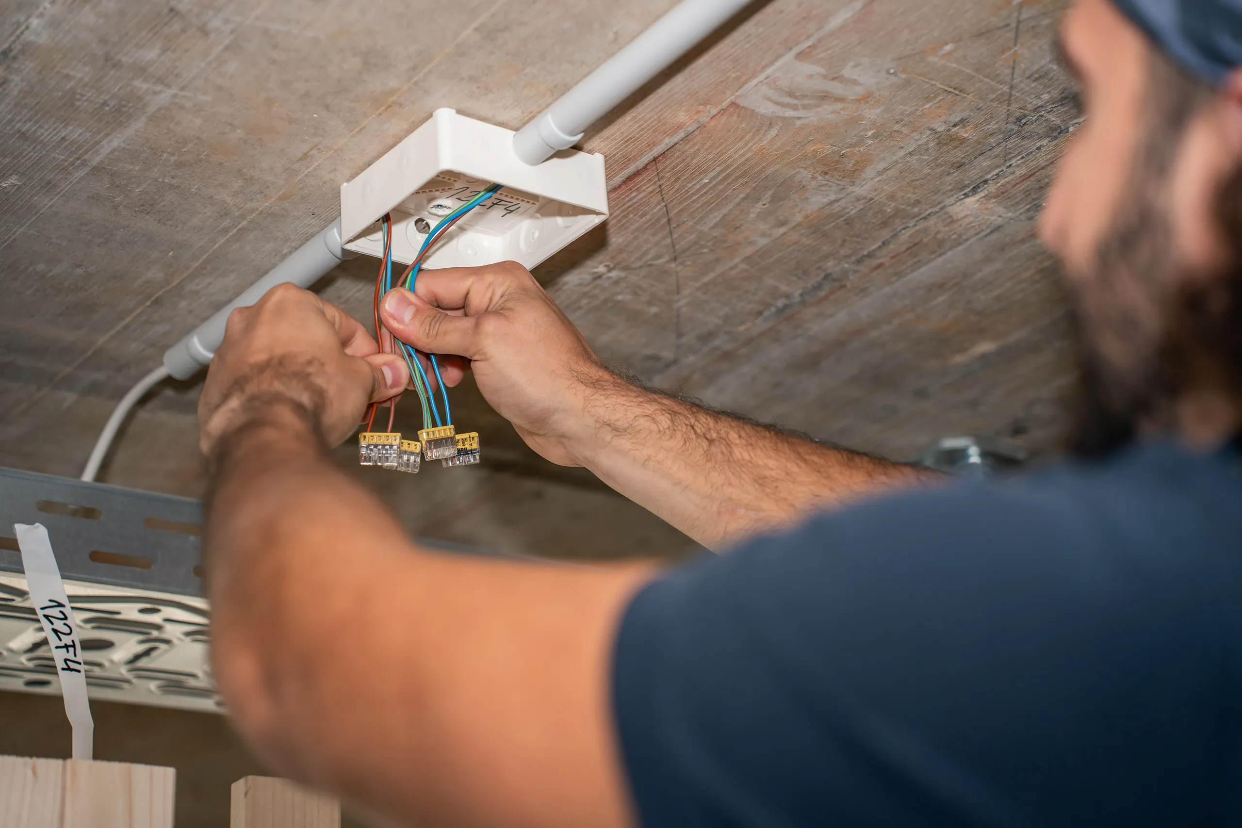 Elektriker der elektro scherzinger ag verdrahtet eine Deckenabzweigdose