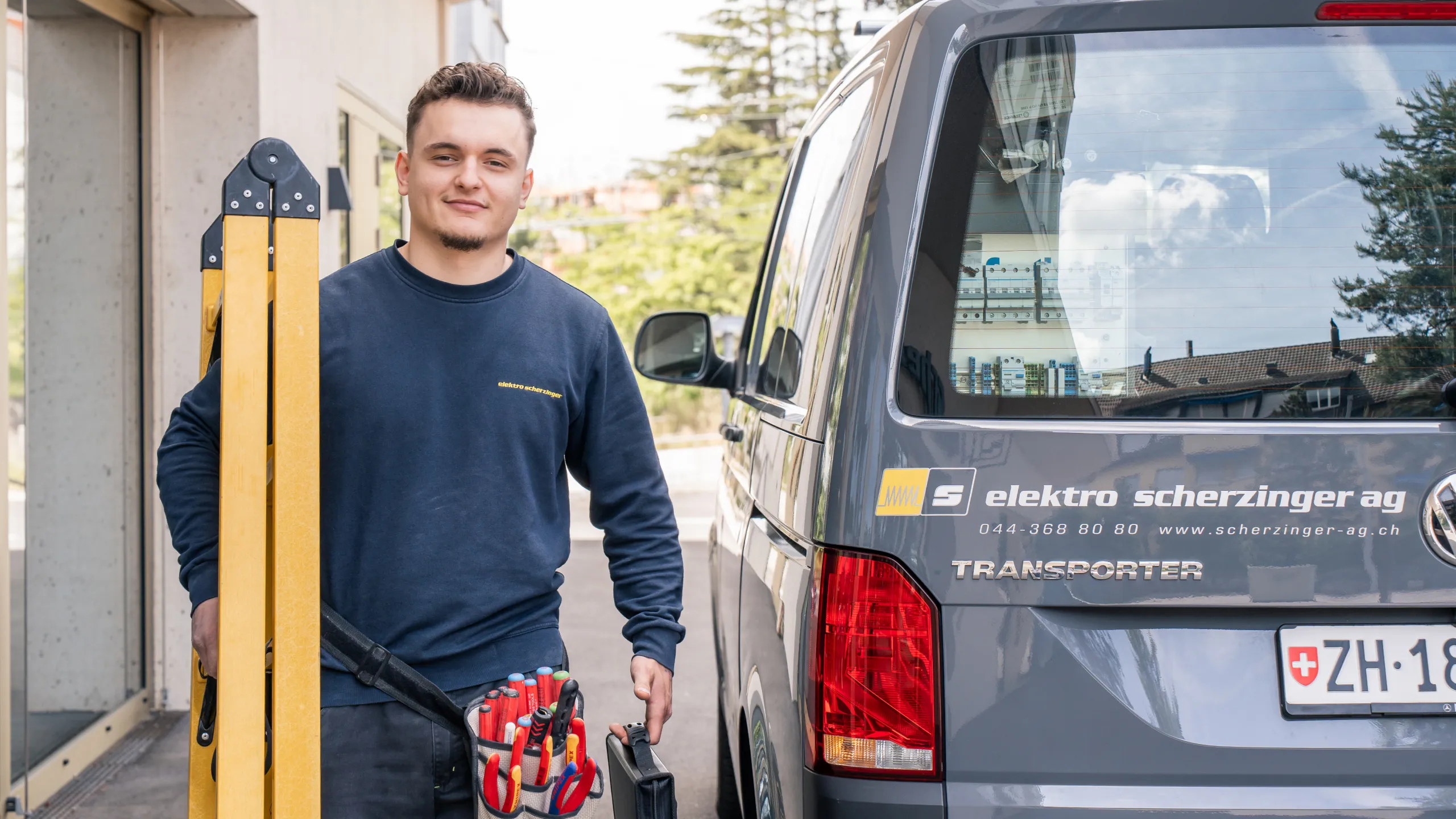 Elektriker der elektro scherzinger ag mit Leiter und Werkzeug vor dem Servicefahrzeug