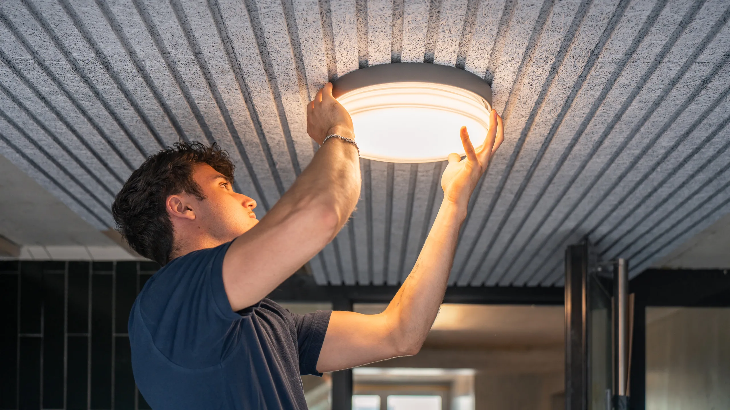 Elektriker der elektro scherzinger ag montiert eine runde LED-Deckenleuchte