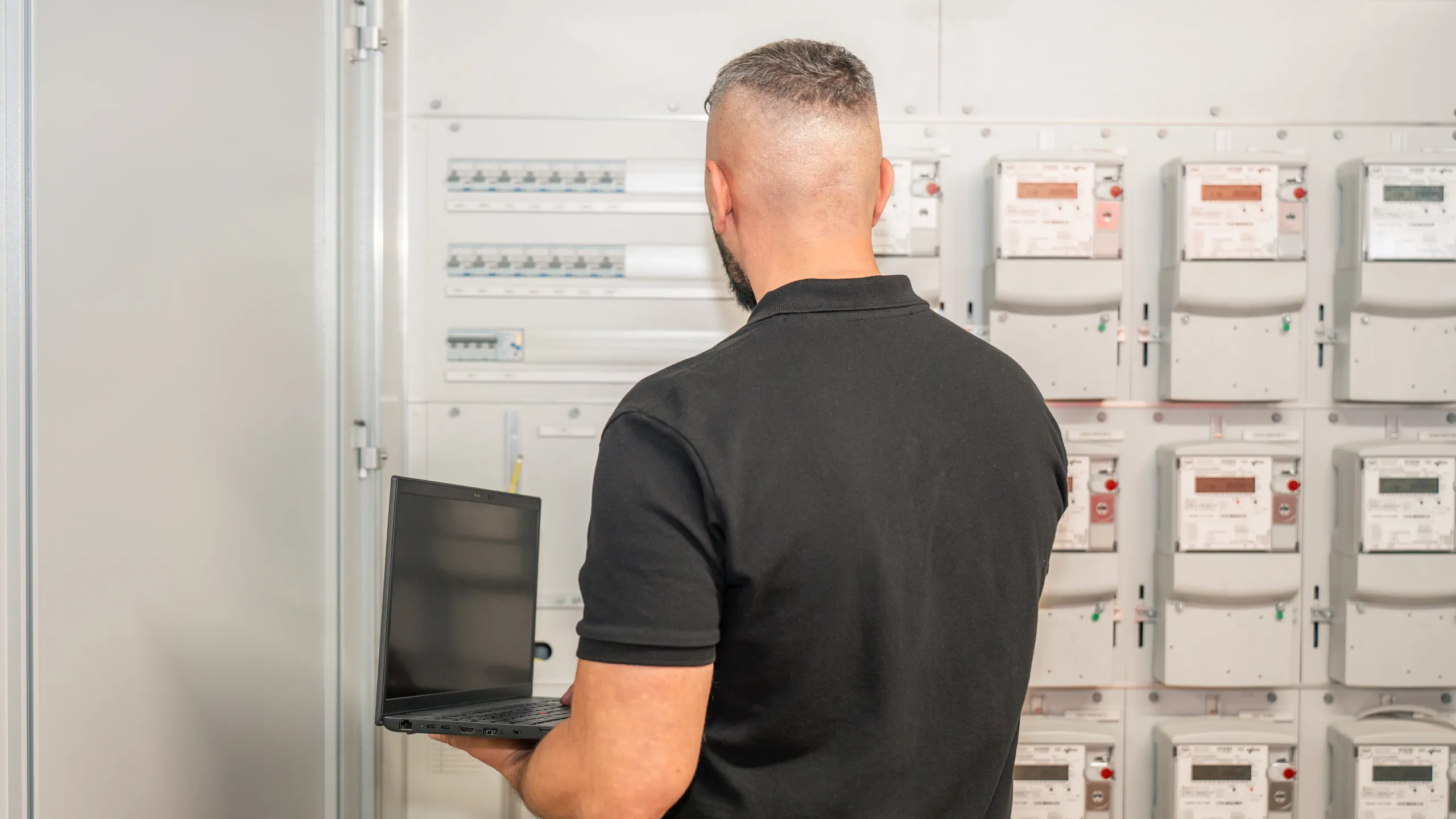 Elektriker der elektro scherzinger ag prüft eine Schaltanlage mit Stromzählern am Laptop